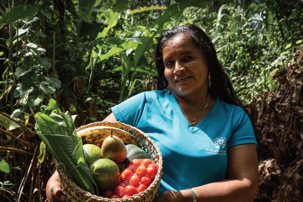 A woman holds a basket of freshly harvested food